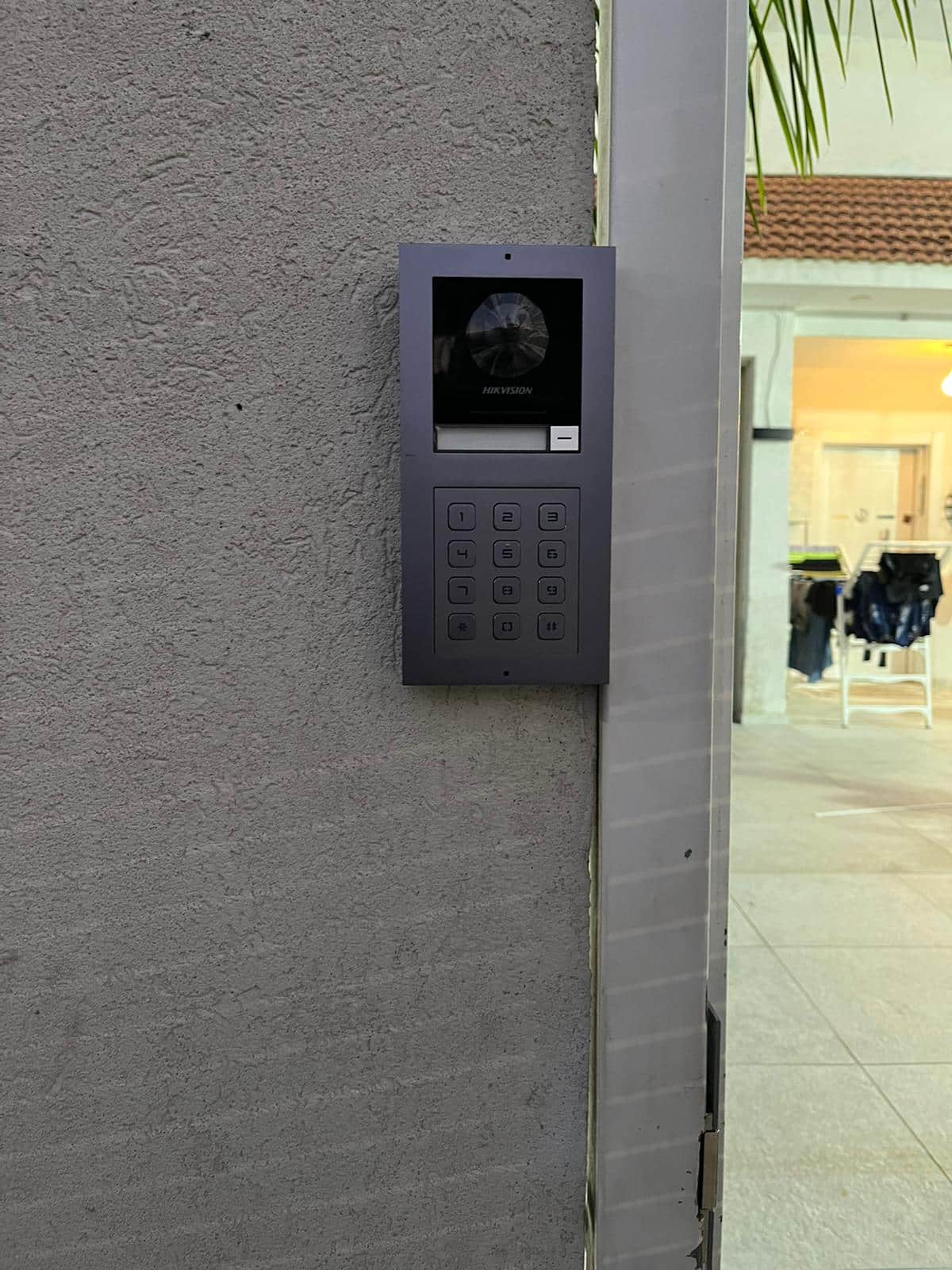 פנל אינטרקום Hikvision עם מצלמה וקודן, מותקן שקוע בקיר חוץ ליד הכניסה