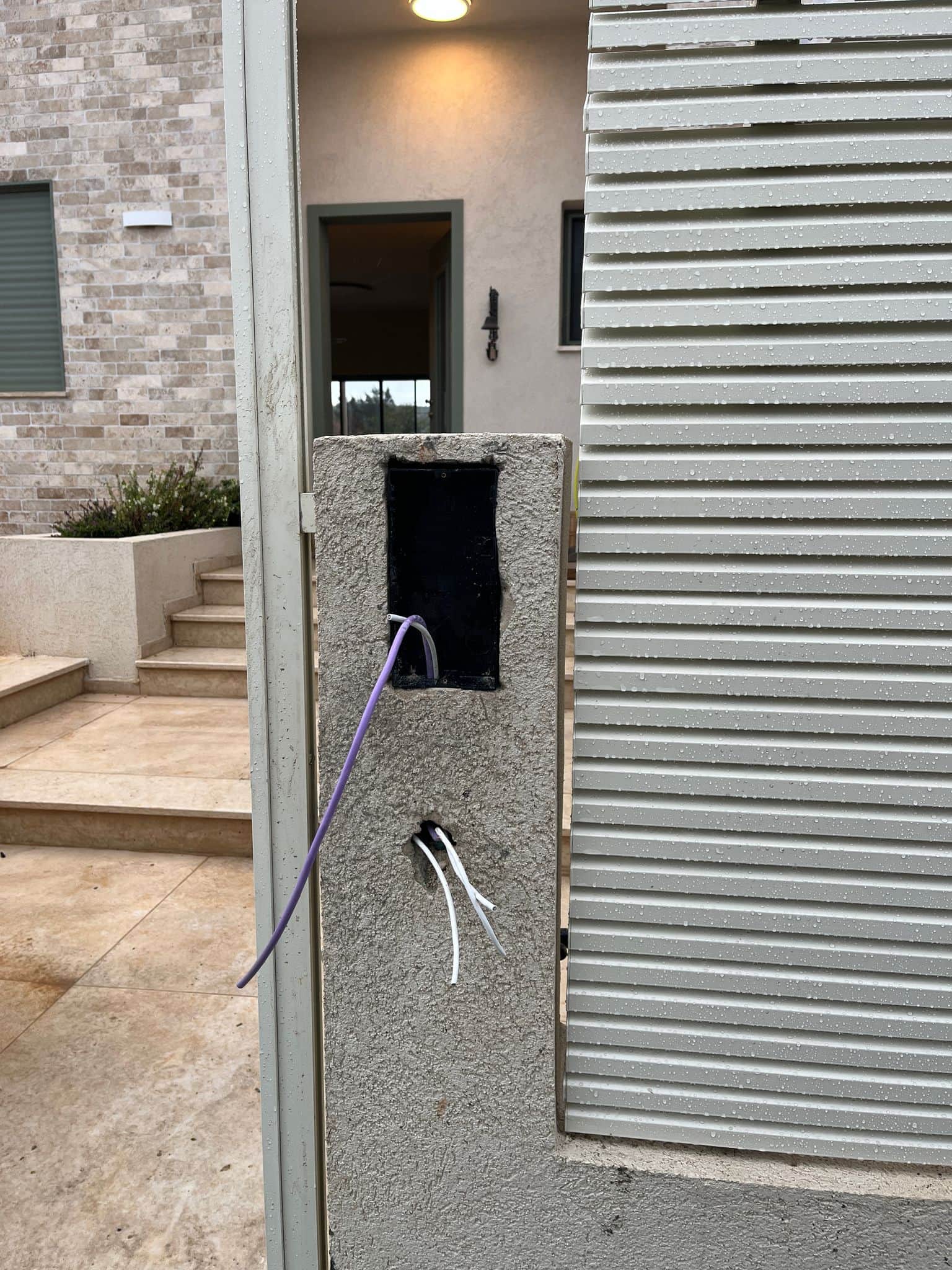 עמוד שער מוכן להתקנת אינטרקום, עם כבלי תקשורת שנמשכו דרך הבטון