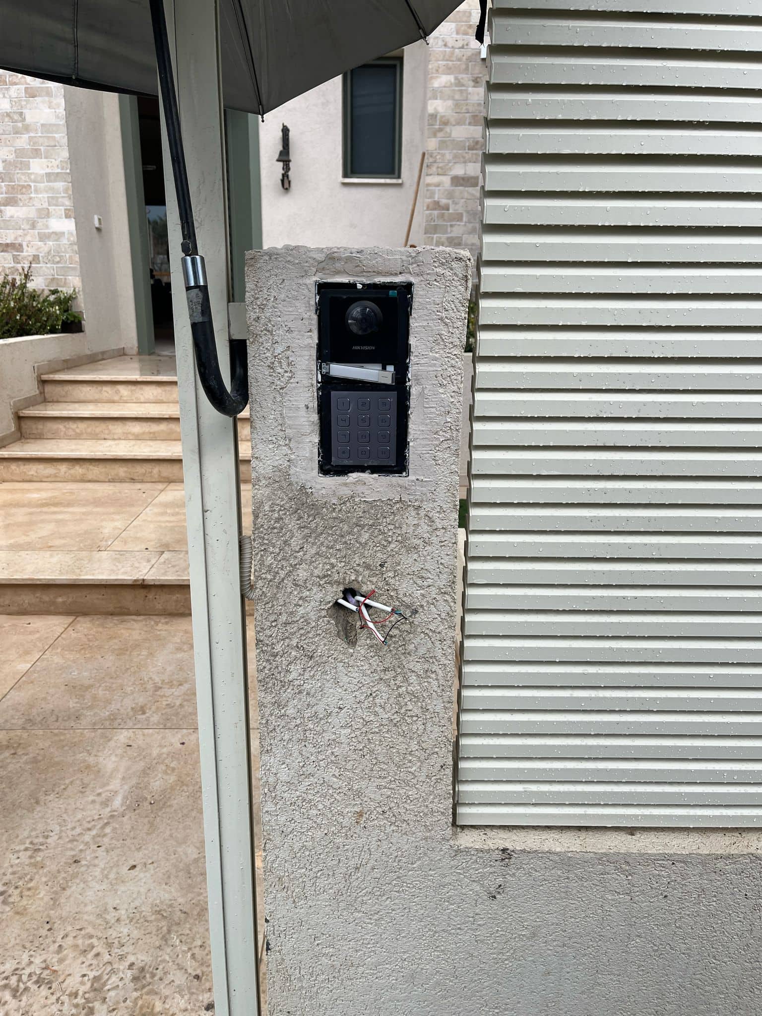 התקנת פנל אינטרקום Hikvision בתוך גומחה בעמוד השער, לפני סגירת החיווט